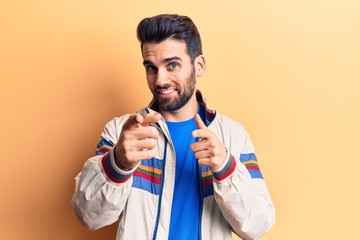 Young handsome man with beard wearing casual jacket pointing fingers to camera with happy and funny face. good energy and vibes.