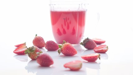 Frezas en primer plano junto a una Jarra con jugo en una mesa blanca. 