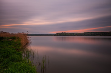 Long exposure sunset view on Ivano-Frankove Yaniv , Yanivskyi Stav Lake and forest. Roztochia Biosphere Reserve, Lviv district, Ukraine. May 2020