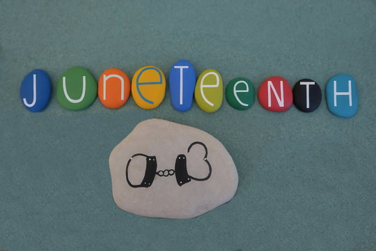 Juneteenth, the oldest nationally celebrated commemoration of the ending of slavery in the United States composed with multi colored stone letters over green sand