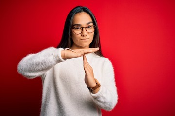 Young beautiful asian woman wearing casual sweater and glasses over red background Doing time out...