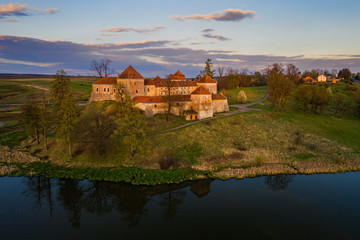 Naklejka na ściany i meble The beautiful medieval castle in the village of Svirzh Swirz in Western Ukraine in late calm evening, aerial view. Mighty fortress is popular tourist destination and place of summer opera festival