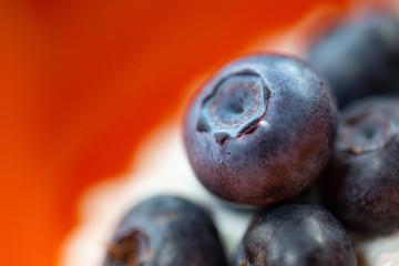 Blueberries in orange bowl with chocolate drizzle.
