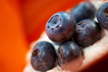 Blueberries in orange bowl with chocolate drizzle.