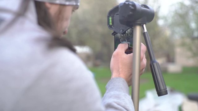 The guy prepares the phone for video shooting, a smartphone on a tripod