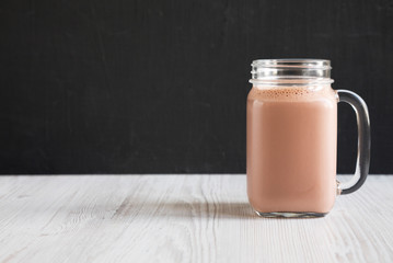 Homemade New England Chocolate Milkshake in a Glass Jar Mug, side view. Copy space.
