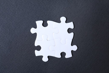 Blank white puzzle pieces on black background, flat lay