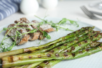 Tasty meat served with grilled asparagus on plate, closeup