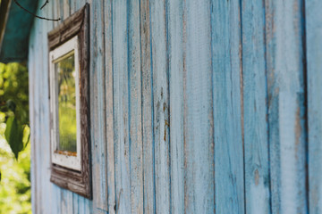 Blue weathered wooden texture of old hut with a window. Selective focus. 