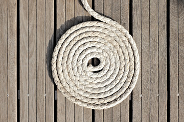 A mooring line neatly coiled on a teak deck.
