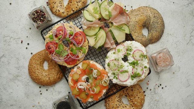 Delicious Bagel sandwiches with creamy cheese, ham, hummus, salmon and vegetables