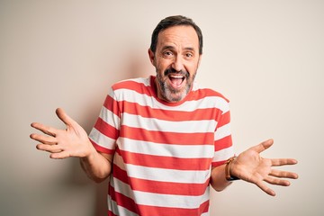 Naklejka premium Middle age hoary man wearing casual striped t-shirt standing over isolated white background clueless and confused expression with arms and hands raised. Doubt concept.