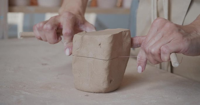 Female potter cutting piece of pottery clay close-up