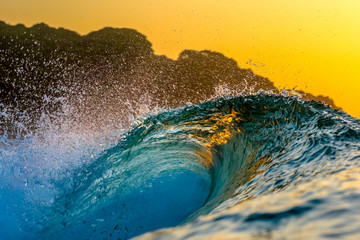 Surfing In Japan Close up of wave breaking a Sunrise.
A close up of a breaking wave during sunrise in Japan with a headland in the background the suns rays are piercing the wave & the texture looks li