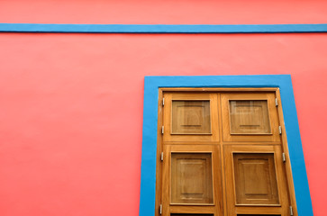 A pink wall with blue deco lines and a perfect varnished wooden shutter. An abstract architecture detail, offset, with copy space.