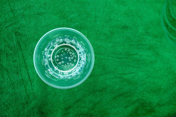 A glass with sparkling water on green background.