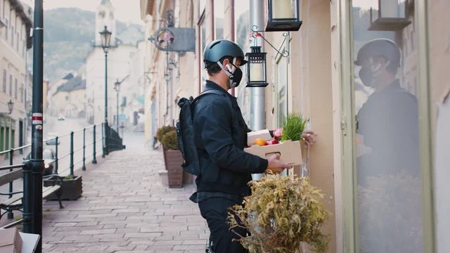 Delivery man courier with face mask delivering groceries in town.