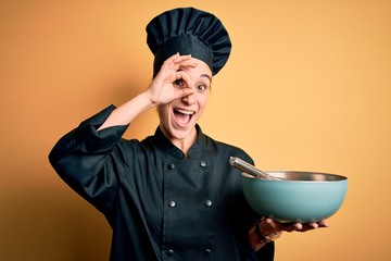 Young beautiful chef woman wearing cooker uniform and hat holding bowl and whisk with happy face...
