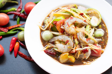 Papaya salad with shrimp in white bowl isolated on black background. Thai food delicious and popular       