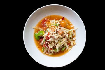 green papaya salad in white bowl isolated on black background. Thai food delicious and popular