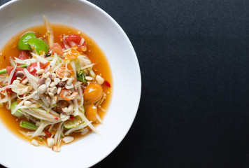 green papaya salad in white bowl isolated on black background. Thai food delicious and popular