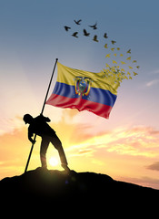 Ecuador flag turn to birds while being planted by a man on a hill during sunrise.