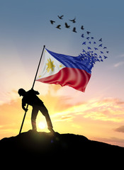 Philippines flag turn to birds while being planted by a man on a hill during sunrise.