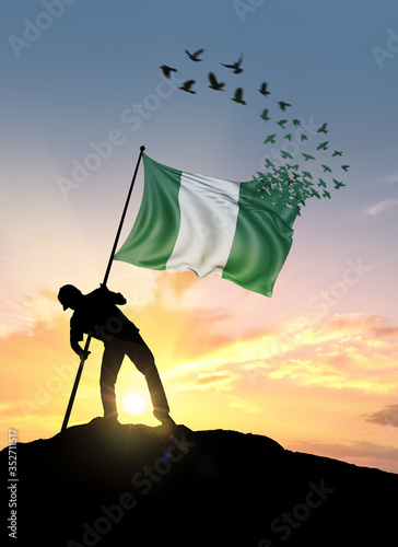 Nigeria flag turn to birds while being planted by a man on a hill during sunrise.