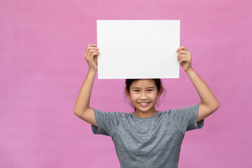Little asian girl holding white paper isolated on pink background.