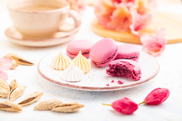 Purple macarons or macaroons cakes with cup of coffee on a white concrete background. Side view, close up, selective focus.