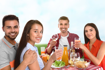 Group of friends having picnic at table in park