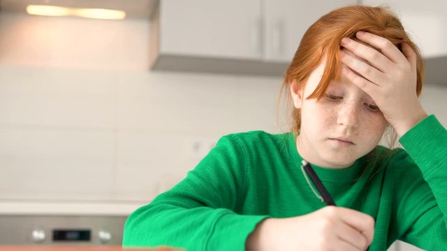 Cute red-haired girl tired of doing lot of homework, homeschooling program