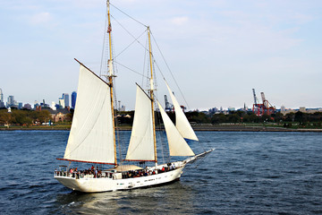 New York, NY, USA. September 20, 2017. Yacht with white sails and passengers on the background of Governors Island near New York.