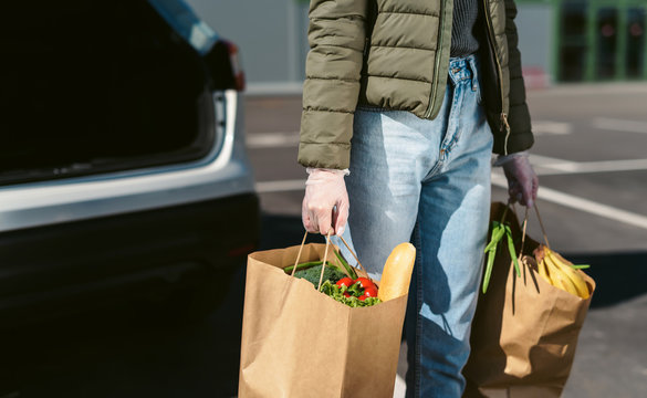 A Young Woman With Grocery Bags From A Supermarket. Car Trunk At Background. Social Distancing: Face Mask, Disposable Gloves To Prevent Infection. Food Shopping During Coronavirus Covid 19 Epidemic