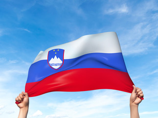 Two hands are holding a Slovenia flag - flowing through the wind. 3D Illustration.