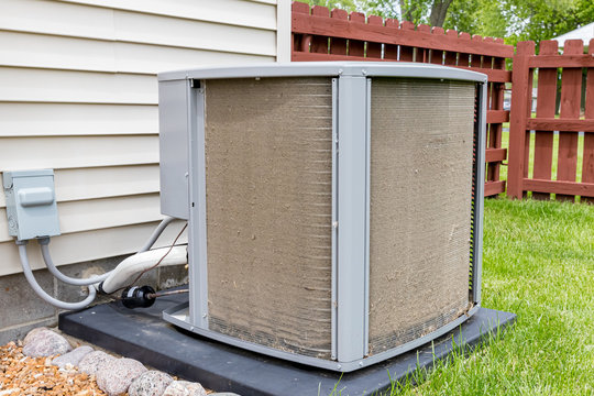 Dirty air conditioning unit. Condenser coil full of dirt and grass debris. Concept of home air conditioner repair, service, cleaning and maintenance