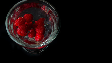 
Raspberries in a water glass. Free entry space.