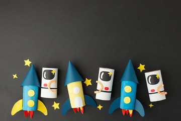 School kindergarten crafts, paper spaceship, shuttle, astronaut on black background with copy space for text. Party, start up launch concept, diy, creative idea from toilet tube, recycle