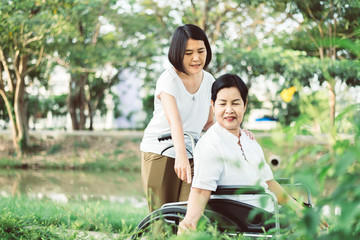 Senior care insurance concept,Caregiver take care to elderly asian woman sitting on wheelchair at...