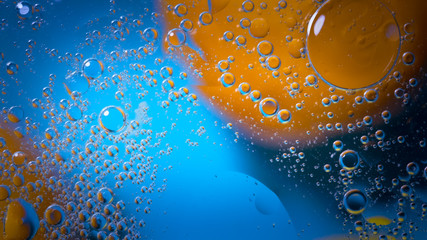 High quality abstract close-up of a bright colourful natural bacground with lemons and oranges giving orange blue and yellow colours with the water and oil bubbles moving around the picture and mixing