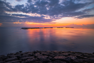 Sunrise seascape. Amazing water reflection. Cloudy sky. Sunlight at horizon. Nusa Dua beach, Bali, Indonesia.