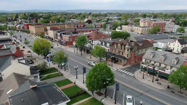 Aerial establishing shot of Main Street, Small Town America, storefronts and colonial homes in United States historic town