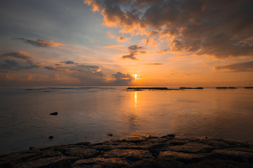 Sunrise seascape. Amazing water reflection. Cloudy sky. Sunlight at horizon. Nusa Dua beach, Bali, Indonesia.