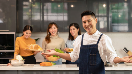 four young asian friends having fun together in home kitchen cooking food for dinner during coronavirus pandemic lock down at self qurantine house, selective focused