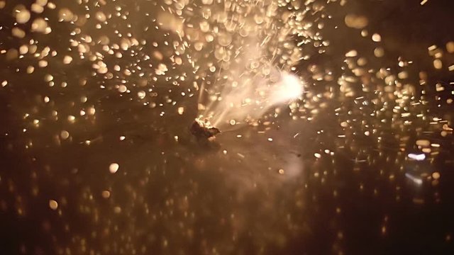 Strong explosions with bright flashes and scattering of many sparks around in the dark. Macro. Closeup. Shallow depth of field. Slow motion. High speed camera. V-log - High Dynamic Range