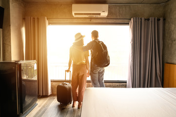 Portrait of young couple tourist standing nearly window, looking to beautiful view outside in...