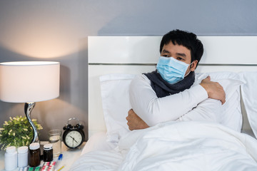 sick man in medical mask feeling cold and suffering from virus disease and fever in bed,...