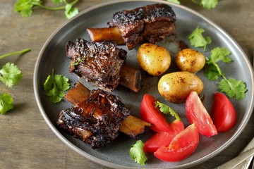 stewed short ribs with new potatoes.
long stewed meat. serving with tomatoes and herbs