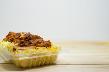 A plastic pack of lamb mandy rice on wood background. The best arabic food. Selective focus.