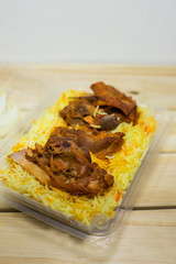 A plastic pack of lamb mandy rice on wood background. The best arabic food. Selective focus.